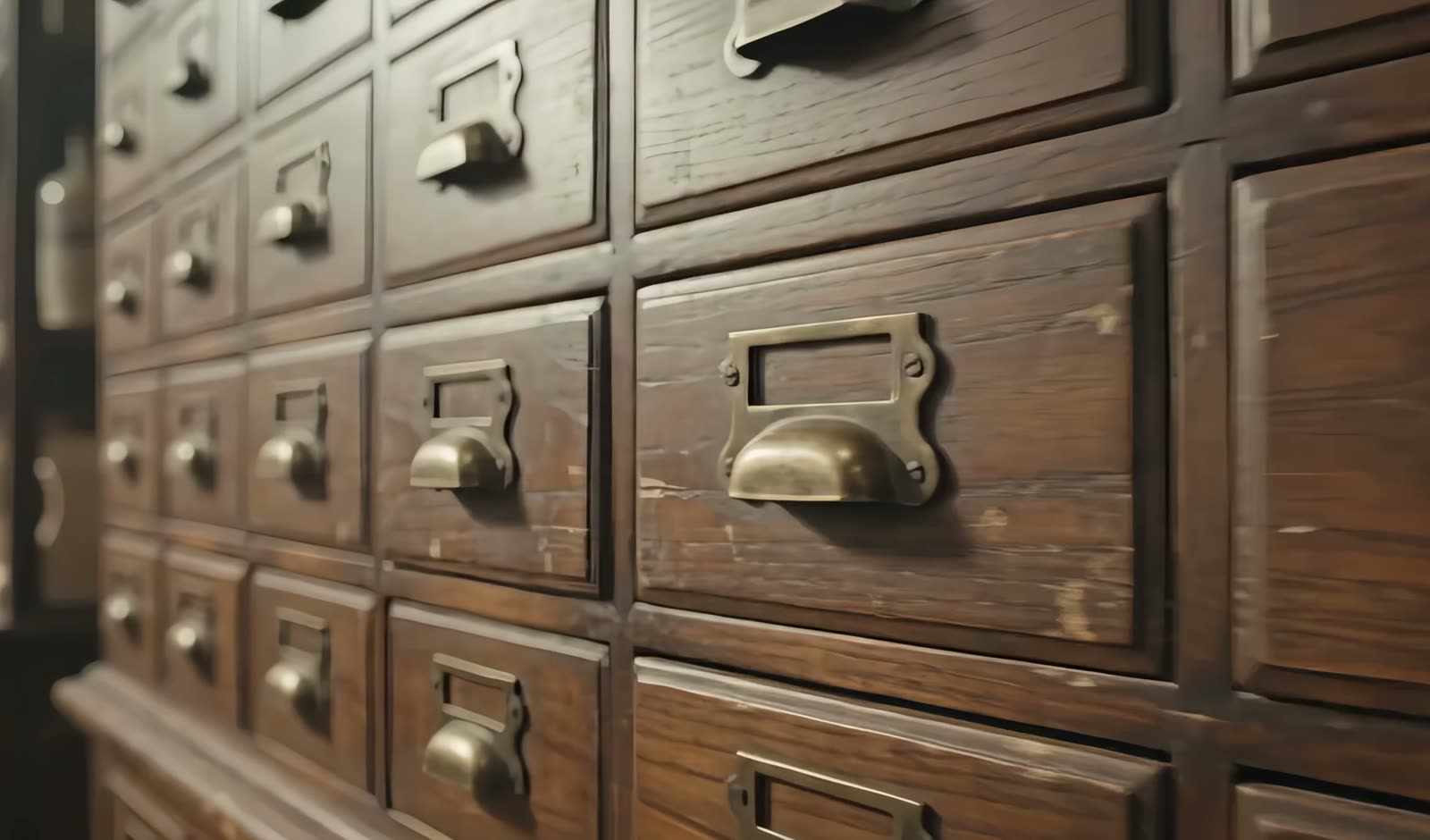 The face of a hundred-drawer Chinese medicine apothecary cabinet, brass drawer pulls in raking light.